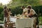 Cute girl helping her mother serve table with homemade food for outdoor dinner