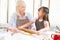 Cute girl and her mother bake kneading dough in the kitchen at h