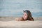 Cute girl with long hair and bow headband lying on the sand