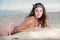 Cute girl with long hair and bow headband lying on the sand