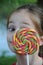 Cute girl lurks behind a giant lolly