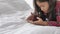 Cute girl lying on bed and looking at smart phone and social media entertainment. People lifestyle and Education. Child and kid