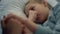 Cute girl lying hospital bed portrait. Mother gently holding child hand closeup.