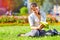 Cute girl with notebook sitting in colorful park