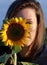 Cute girl outdoor in the wilderness with sunflower in front of her face