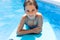 Cute girl playing with a bodyboard in a swimming pool.