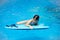 Cute girl playing with a bodyboard in a swimming pool.