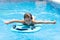 Cute girl playing with a bodyboard in a swimming pool.