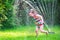 Cute girl playing with garden sprinkler