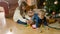 Cute girl playing with her little brother on floor under Christmas tree