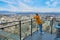 Cute girl posing while standing on balcony of skyscraper high floor with cityscape behind