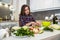 Cute girl prepares a salad of different vegetables and greens for a healthy lifestyle