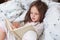 Cute girl reading her favorite fairy tale, child sitting in bed with book, Kid preparing to go to bed, spending pleasant time in