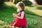 Cute girl in red dress collects wildflowers. happy baby in a good mood.