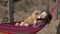 Cute girl relaxing in hammock with shiba inu dog spending leisure time in autumn forest