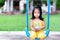Cute girl sat on the blue swing. Child holds jar with lots of coins in his hand. On the loaded bottle, write a sign that says home