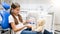 Cute girl sitting in dentist chair and showing her teddy bear how to properly clean teeth