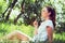 Cute girl sitting in a park and blowing on the dandelion. Natural look.