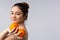 A cute girl smiles tenderly and holds two juicy oranges in her hand. Vitamins concept. Shine and skin care. Gray