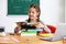 Cute girl with stack of books sitting in classroom