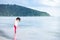 Cute girl stand and watched the sea water splashing at his feet on the sandy beach. Child looked excitedly at her feet.