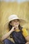 Cute girl in a straw hat, sitting in a field of hay in Eagle Mountain, Ut.