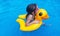 Cute girl in sunglasses swimming with rubber duck in pool