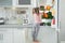 Cute girl taking apple out of refrigerator