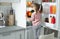 Cute girl taking apple out of refrigerator