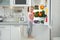 Cute girl taking apple out of refrigerator