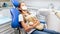 Cute girl with teddy bear sitting in dentist chair in clinic and feeling nervous before treating teeth