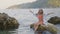 Cute girl teenager shaking long hair on sea stones. Beautiful girl in swimsuit and tunic shaking long hair for photo in