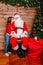 Cute girl telling wish in Santa Claus`s ear near Christmas Tree