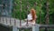 Cute girl with thick beautiful fiery red hair sits on suspension bridge over river and reads book