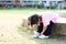 Cute girl is trying to wear tight shoes on her own. Child wear white sneakers. Children get ready to run in the lawn.