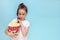 cute girl with a very puzzled look, with a huge glass of popcorn and a pigtail on a blue background with copy space