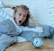 Cute girl waking with alarm clock feeling tired and angry time to go to school early in the morning