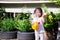 Cute girl was holding yellow watering can  smiling sweetly in garden of small tree in front of house. Children help with housework