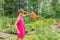 A cute girl with a watering can in her hands watering flowers in the garden.