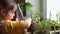 Cute girl watering seedlings on the windowsill first spring flowers. home interior and decoration. Child taking care of