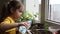 Cute girl watering seedlings on the windowsill first spring flowers. home interior and decoration. Child taking care of