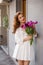 Cute girl in white dress and a beautiful bouquet of tulips.