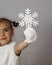 Cute girl with white painted hand holding a white colored snowflake melting down