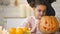 Cute girl in witch costume showing jack pumpkin and smiling, preparing for party