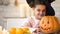 Cute girl in witch costume showing jack pumpkin and smiling, preparing for party
