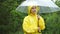 Cute girl in yellow raincoat holds umbrella on rainy day