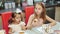 Cute girls are drinking tea with cookies in the kitchen.