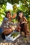 Cute girls picking up grapes in a white wooden crate. Harvest season at a vineyard field. Rural tourism concept