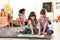 Cute girls reading book on floor while other children playing together