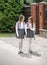 Cute girls in uniform walking to school and chatting